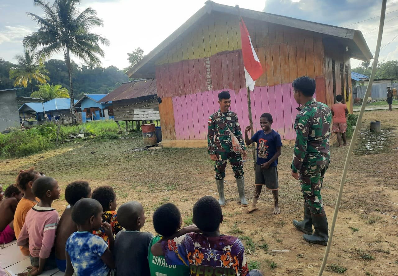 Personel TNI Pos Kawe Satgas Yonif 143/TWEJ bersama anak-anak taman belajar melaksanakan latihan upacara bendera
