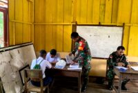 Babinsa Koramil 1710-06/Agimuga Serda Margo Triyanto membantu proses belajar mengajar kepada siswa-siswi SMP Negeri Agimuga