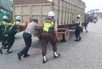 Personel Satlantas Polres Pelabuhan Tanjung Priok bersama beberapa Satpam membantu mendorong truk mogok