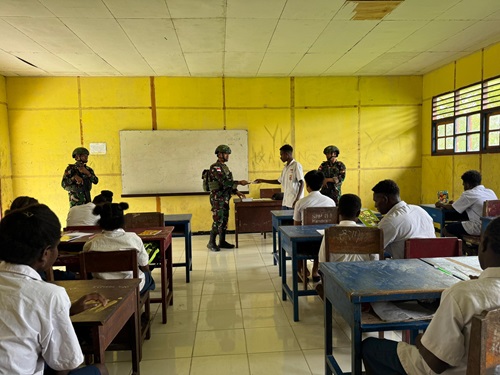 Personel Satgas Kewilayahan RI-PNG Yonif 141/AYJP Pos Kimaam melaksanakan kegiatan pengamanan Parimeter sekaligus berbagi buku tulis