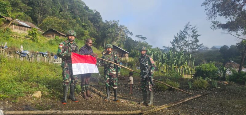 Personel Pos Kulirik Satgas Pamtas Kewilayahan Yonif 715/Motuliato berkeliling ke rumah warga untuk melakukan pemasangan bendera