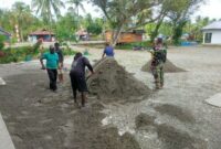 Satgas TMMD bersama warga setempat melaksanakan gotong royong menata lapangan dengan menimbun pasir yang akan digunakan sebagai lokasi