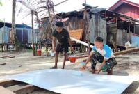 Satgas TMMD ke-128 Kodim 1710/Mimika melaksanakan pengecatan triplek yang akan digunakan sebagai plafon pada MCK umum di Kampung Keakwa