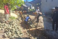 Personel Satgas TMMD bersama masyarakat tampak kompak melaksanakan penggalian tanah sebagai tahap awal pembangunan drainase di Desa Lolobata